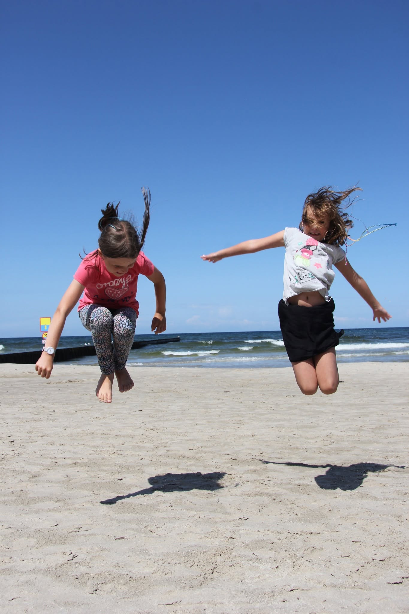 Dwie uczestniczki skaczące na plaży nad Bałtykiem