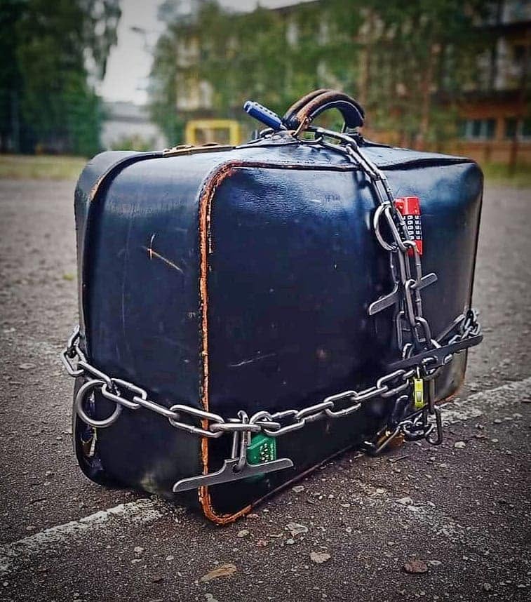 Tajemnicza walizka spięta łańcuchami i zamkami — rekwizyt escape roomu